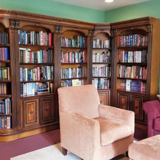 A cozy library corner with armchairs and a bookshelf filled with books.