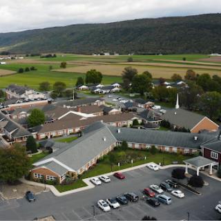 Aerial view of a residential or community building surrounded by fields and hills.