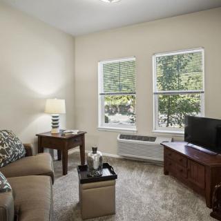 Cozy living room with a sofa, television, and natural light from windows.