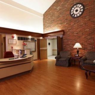 A welcoming reception area with a desk, seating, and a large clock on a brick wall.