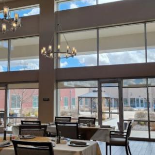 A modern restaurant dining area with large windows and elegant chandeliers.