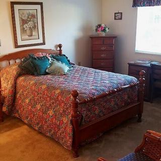 A cozy bedroom with a wooden bed, patterned bedspread, and matching furniture.