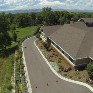 Aerial view of a building surrounded by a winding road, trees, and an expansive sky.