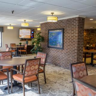 A cozy dining area with tables and chairs, featuring brick walls and warm lighting.
