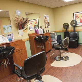 An empty hair salon with chairs and hairdressing stations.