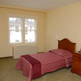 A simple bedroom with a single bed and a window.