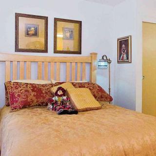 A cozy bedroom with decorative pillows and framed artwork.