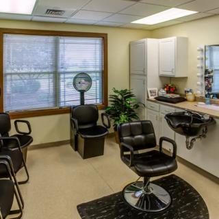 An empty hair salon with styling chairs and a mirror.