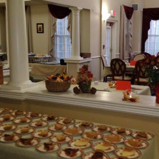 A cozy dining area with autumn-themed decorations and a table filled with assorted desserts.