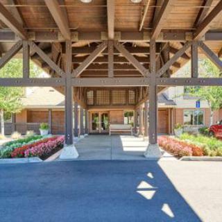 The entrance of a building with wooden beams and manicured landscaping.