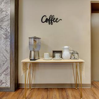 A stylish coffee station featuring a sleek table, decorative items, and a refreshing beverage dispenser.
