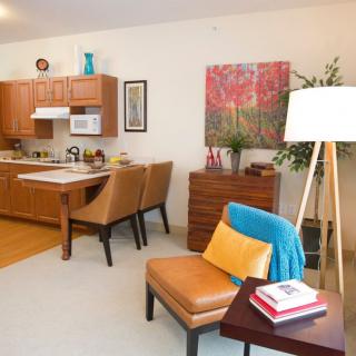 A cozy living space featuring a modern kitchen and comfortable seating area with colorful accents.