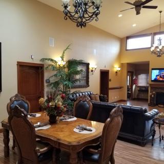 Spacious living and dining area with elegant wooden furniture, chandeliers, and a cozy seating arrangement.