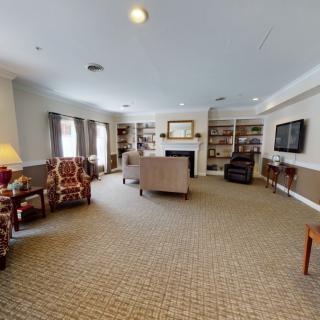 A spacious living room featuring comfortable seating, a fireplace, and bookshelves.