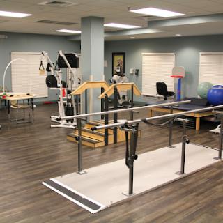 A well-equipped rehabilitation gym featuring various exercise machines and therapy tools.