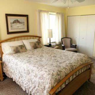 A cozy bedroom with a floral bedspread and natural lighting.
