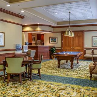 A cozy recreation room featuring a billiards table, seating area, and warm lighting.