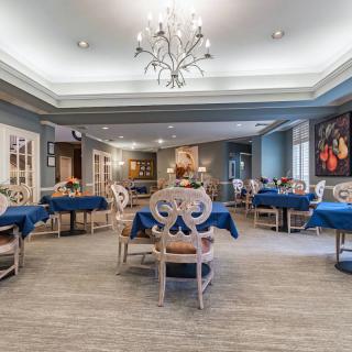 An elegant dining room with neatly arranged tables and a centerpiece chandelier.