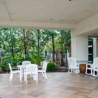 A cozy outdoor patio with white furniture surrounded by lush greenery.