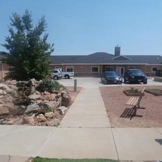 A building with a parking lot and landscaped walkway featuring benches and rocks.