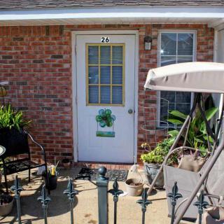 A cozy patio with outdoor furniture and potted plants in front of a brick house.