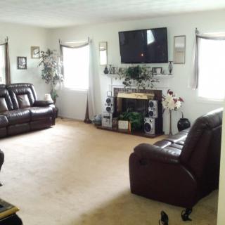 A spacious living room with leather sofas, a mounted television, and a decorative fireplace.