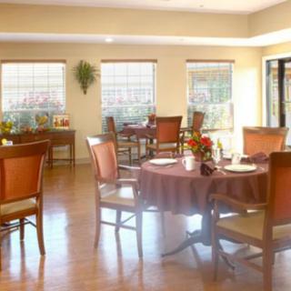 A cozy dining room with multiple tables and chairs, featuring large windows and tasteful decor.