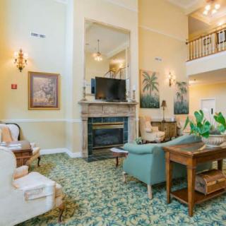 A spacious living room with high ceilings, featuring a fireplace and elegant furniture.