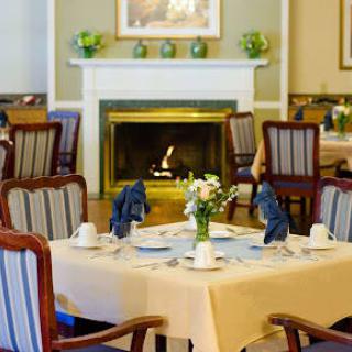 An elegantly set dining room with a cozy fireplace in the background.