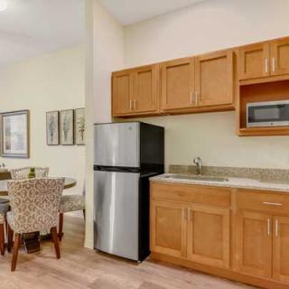 A modern kitchen with wooden cabinets and a dining area.