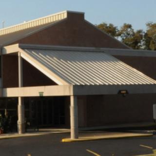 A commercial building with a prominent entrance and an adjacent parking lot.