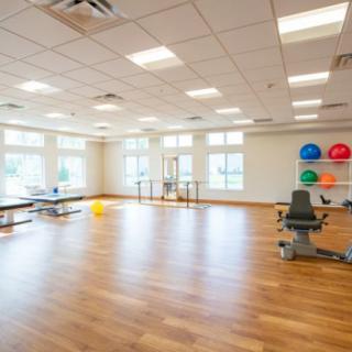 A spacious and modern exercise room with a wooden floor, equipped with fitness equipment and colorful exercise balls.