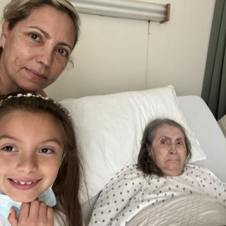 A woman and a child visiting an elderly woman in a hospital bed.