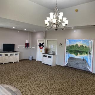 A cozy living room with a chandelier and a decorative wall painting.