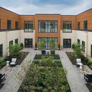 A modern courtyard featuring lush greenery and comfortable outdoor seating.
