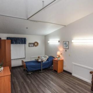 A clean and organized hospital room with a single bed, bedside table, and basic decor.