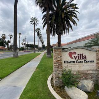 Entrance to Villa Health Care Center, surrounded by palm trees and a scenic pathway.