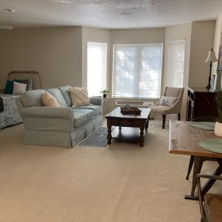 A cozy living room with a sofa, coffee table, and large windows.