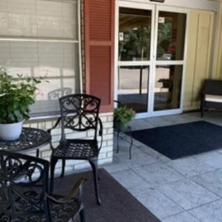 A small outdoor seating area with a table, chairs, and a potted plant near the entrance of a building.