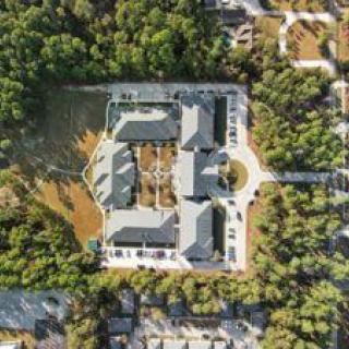 Aerial view of a large building complex surrounded by trees and residential areas.