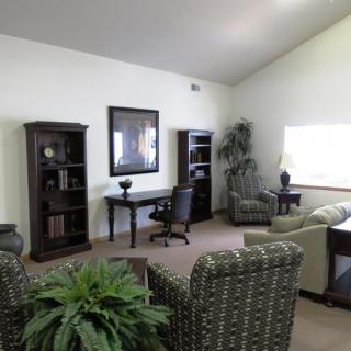 A well-lit office space featuring a desk, bookshelves, and comfortable seating.