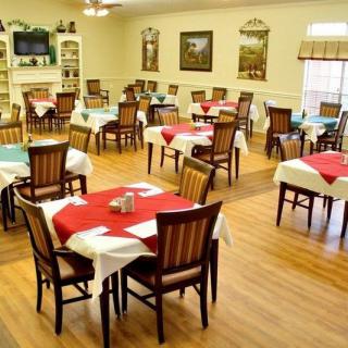 A well-arranged dining area with multiple tables and chairs, featuring colorful tablecloths and a wooden floor.