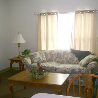 A cozy living room with a floral sofa, wooden coffee table, and soft lighting.