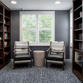 A cozy reading nook featuring two chairs and bookshelves in a home library.