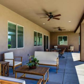 A cozy outdoor patio area with comfortable seating and ceiling fans.