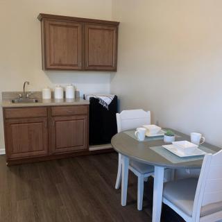 A compact kitchenette with wooden cabinets, a small dining table, and chairs.
