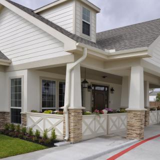A modern residential house with a covered porch and well-maintained front yard.
