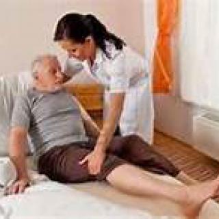 A nurse assisting an elderly man in a care setting.