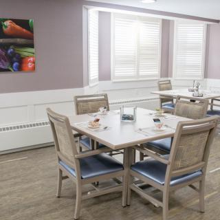 A modern dining area featuring a neatly set table with four chairs and colorful artwork on the wall.