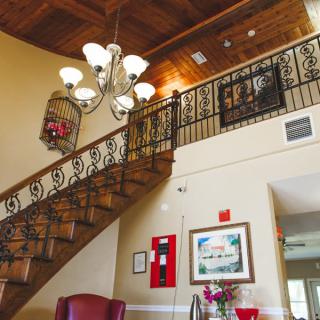 Elegant interior featuring a staircase with ornate railing and a chandelier.